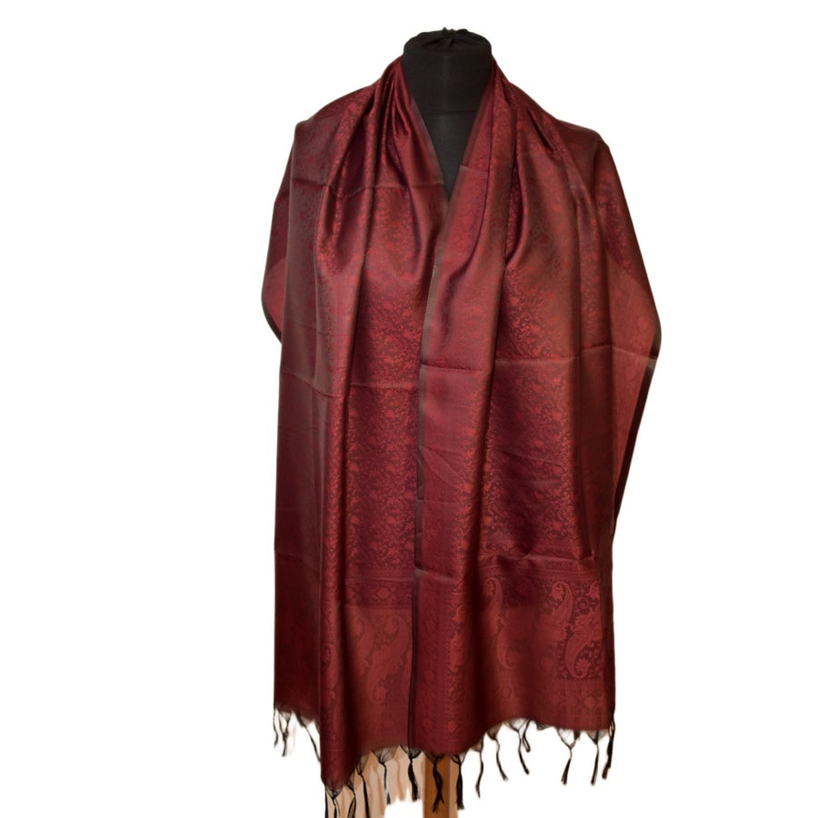 Red scarf with intricate patterns draped over a mannequin on a white background