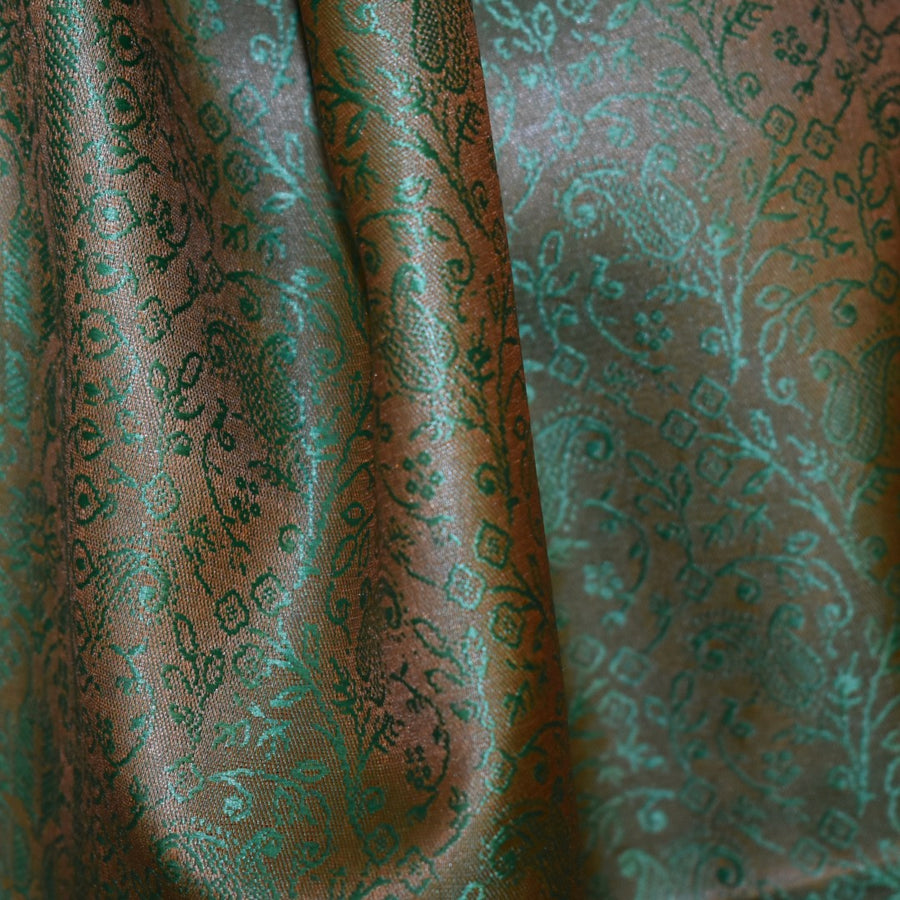 Textured fabric with intricate green pattern on a brown background
